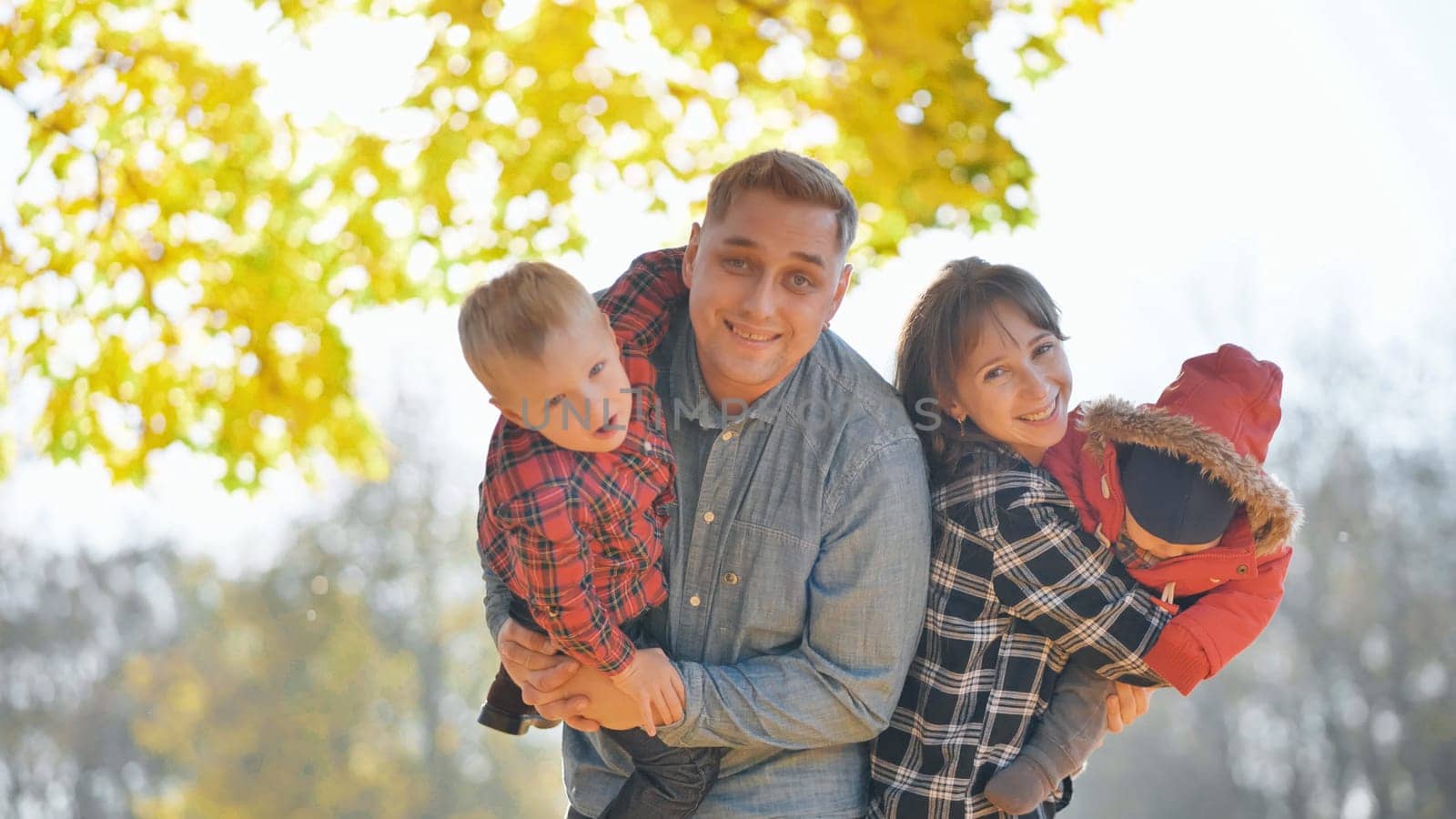 A young, funny family with kids in the park in the fall