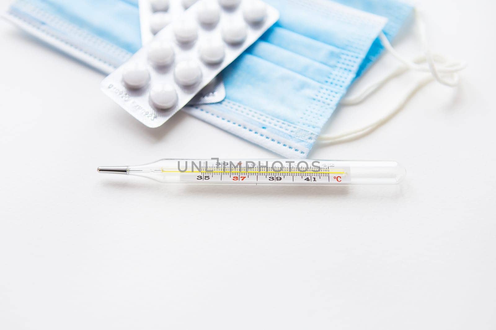 Preparation for vaccination against covid-19. Thermometer, pills, medical mask on a white table. View from above