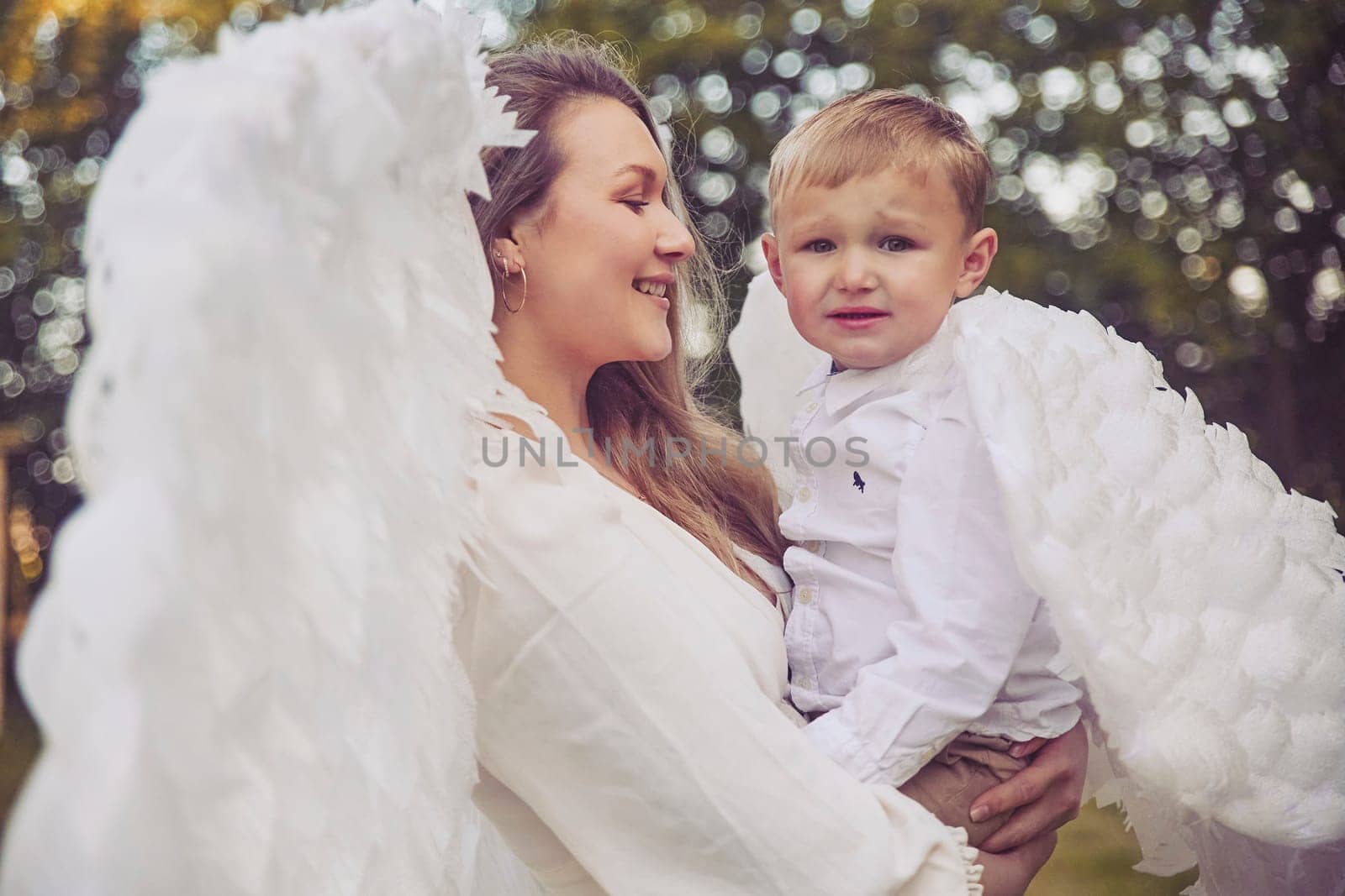 Olstrup, Denmark, June 6, 2023: Girl angel with her son in the evening garden