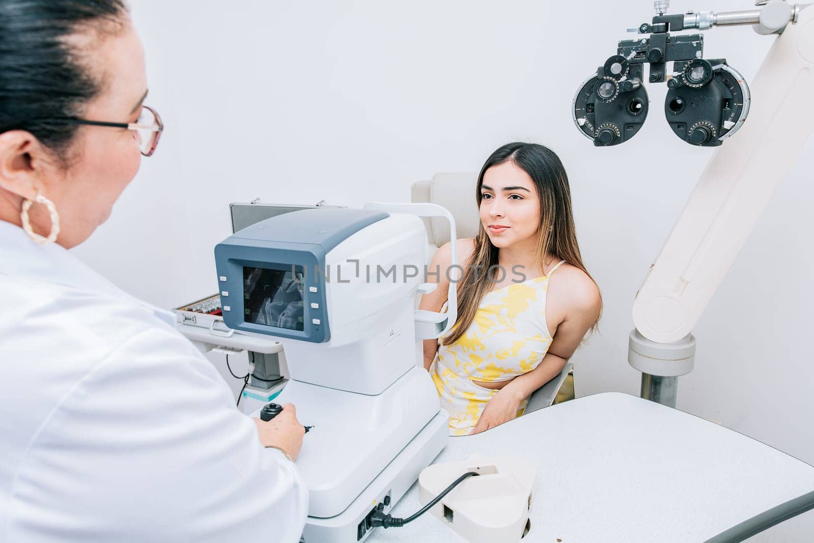 Woman patient having consultation with optometrist in office. Optometrist with female patient in the autorefractor by isaiphoto