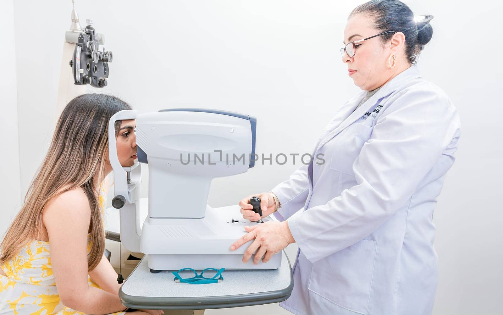 Optometrist checking the eyesight of a patient with an autorefractor. Oculist doing eye exam to female patient by isaiphoto