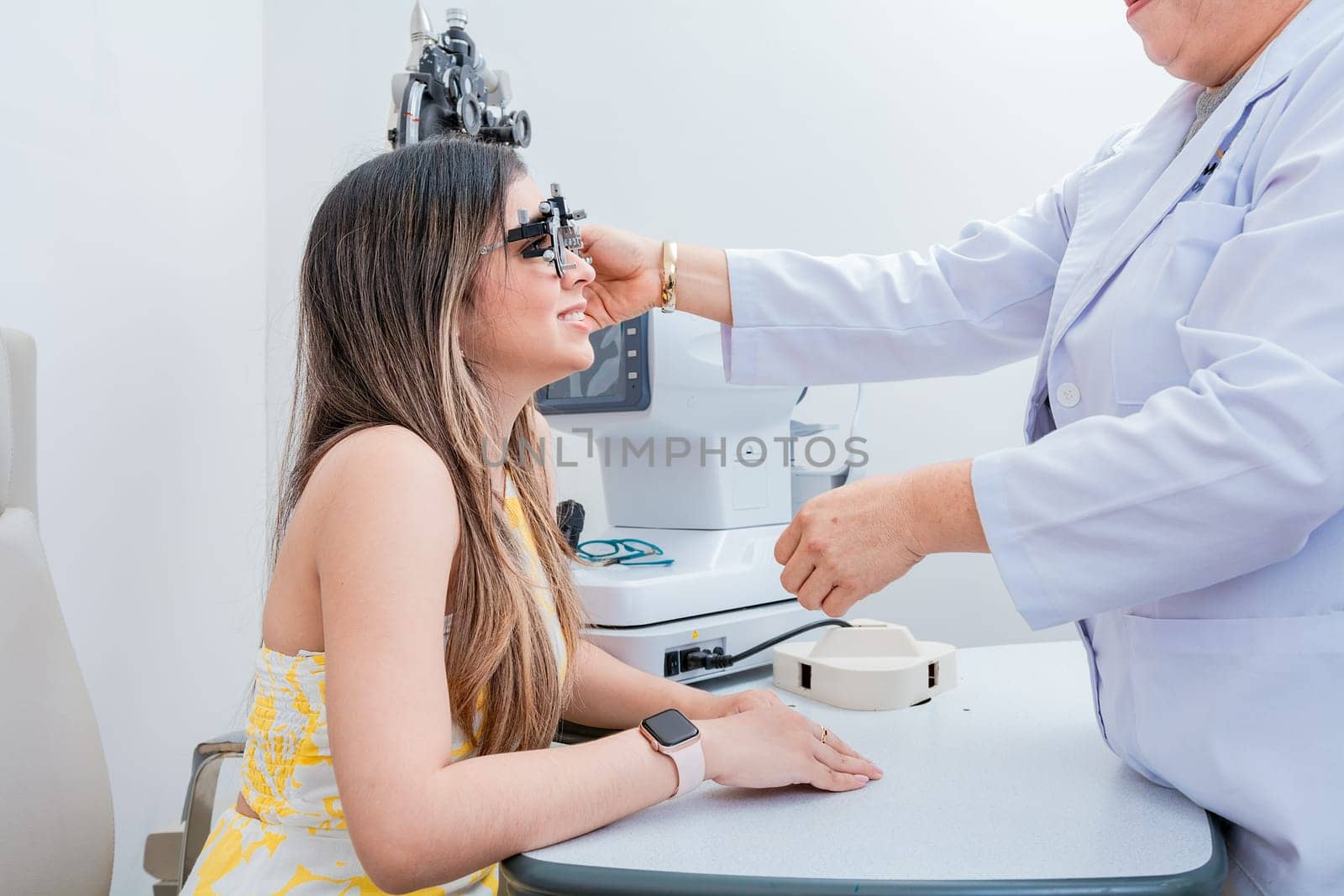 Optometrist woman examining patient with trial frame in office. Optometrist with young patient with optometrist trial frame by isaiphoto