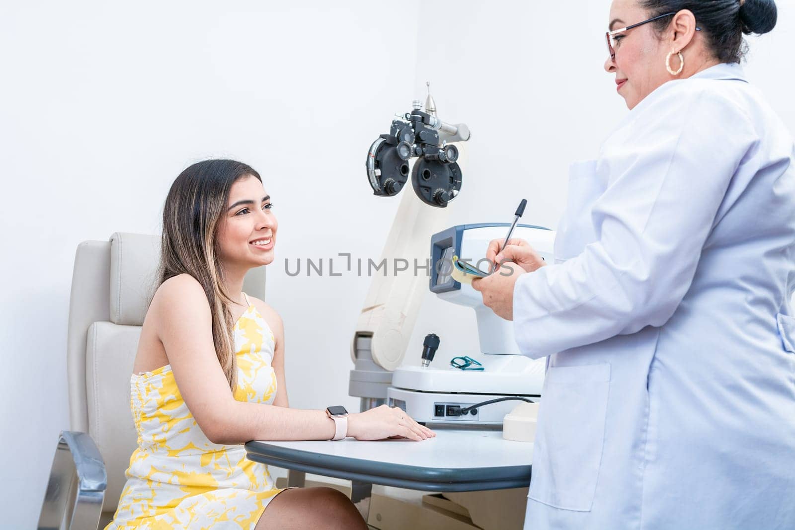 Optometrist with female patient taking notes in office. Female patient having consultation with optometrist in office