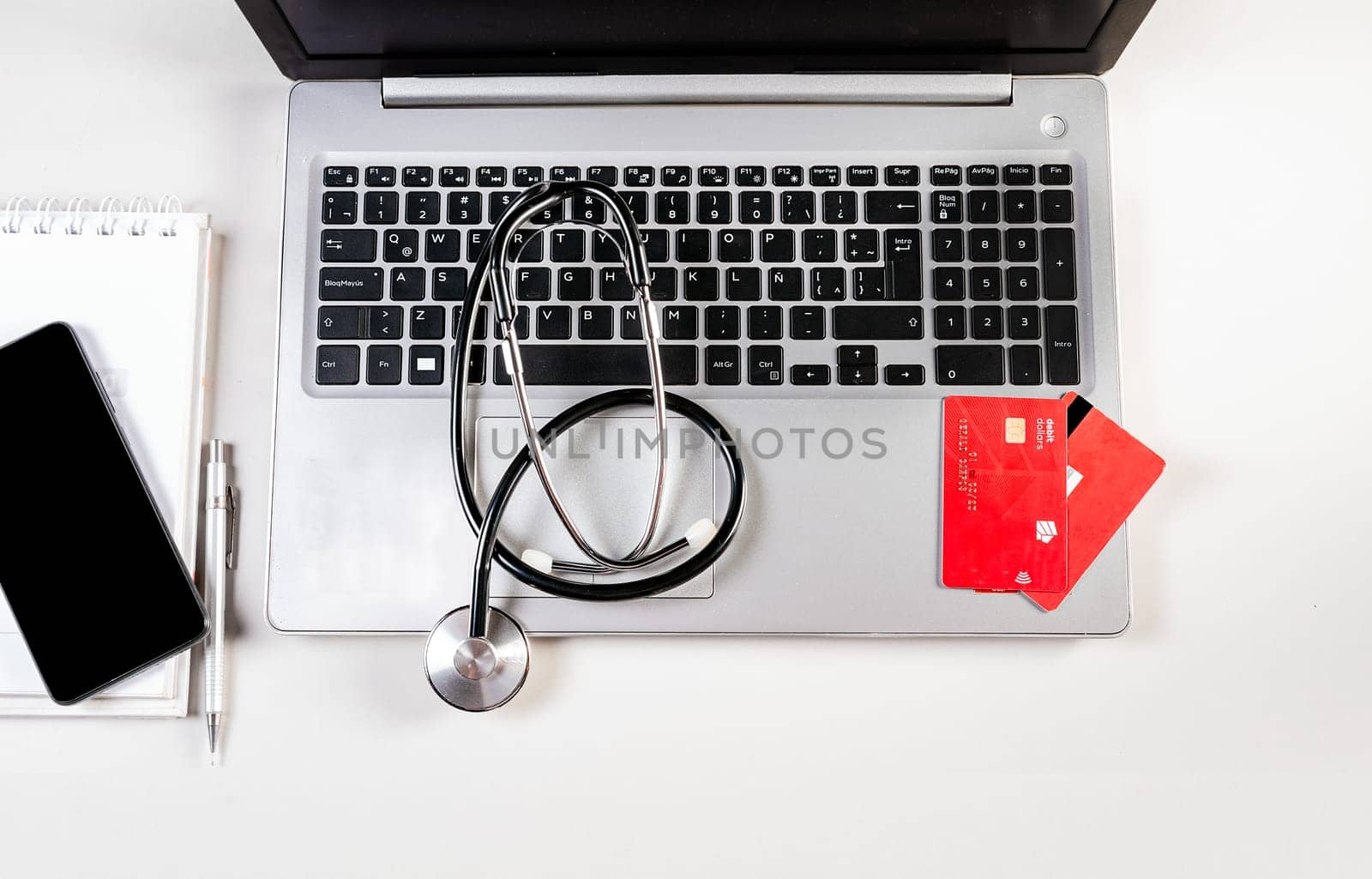 Stethoscope with credit cards on keyboard. Stethoscope on laptop keyboard with credit cards by isaiphoto
