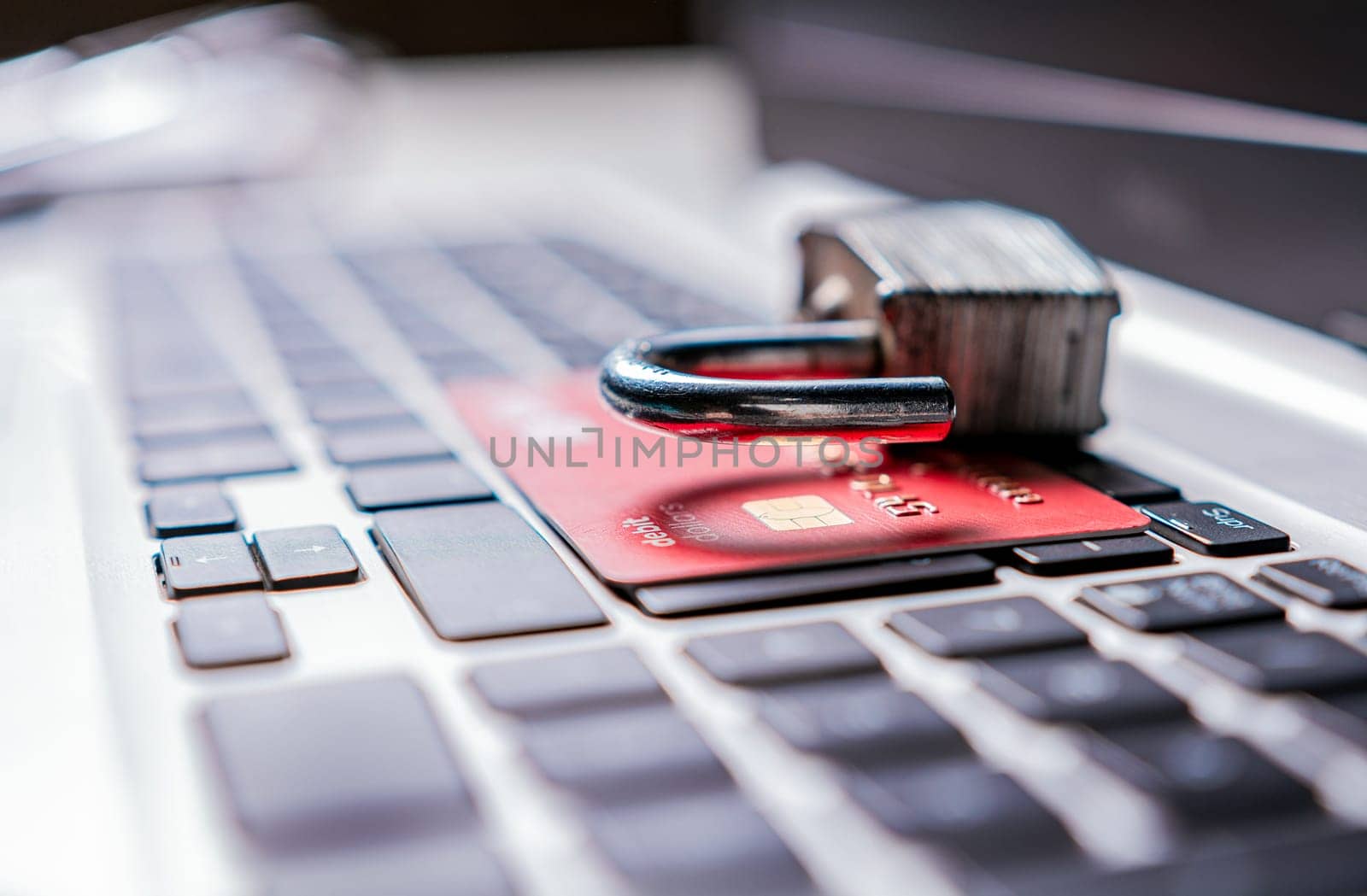 Open padlock with credit card on keyboard. Concept of theft of information on credit cards. Padlock on top of credit card on laptop keyboard