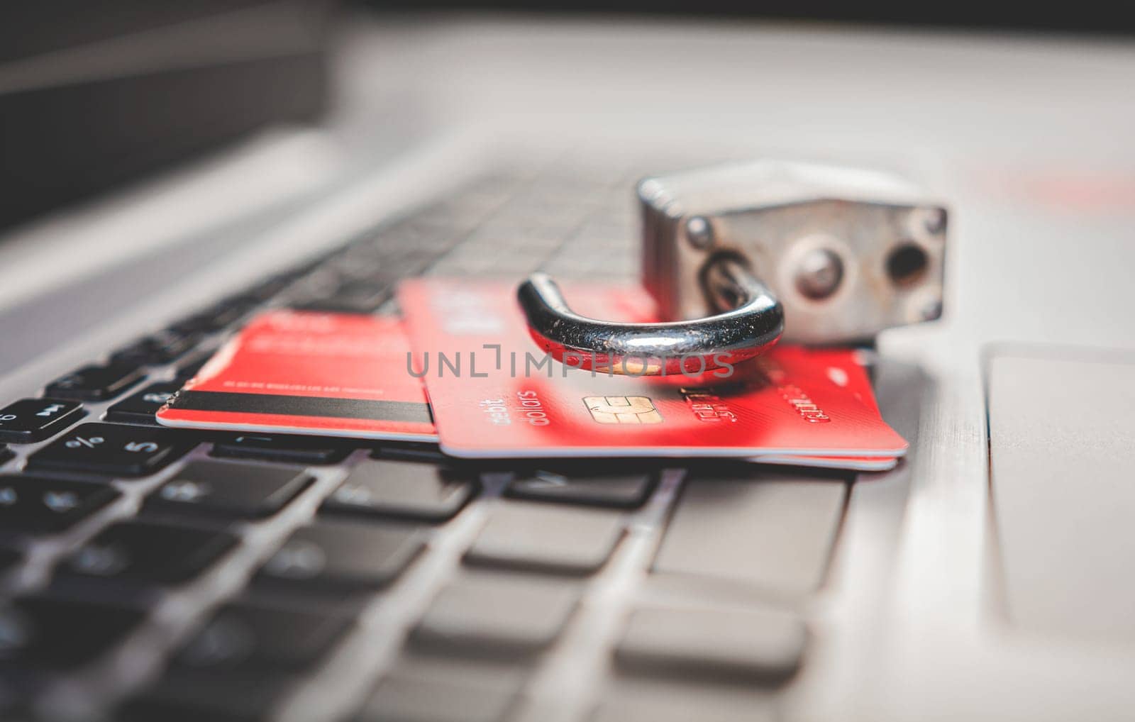 Concept of theft of information on credit cards. Padlock on top of credit card on laptop keyboard, Open padlock with credit card on keyboard by isaiphoto