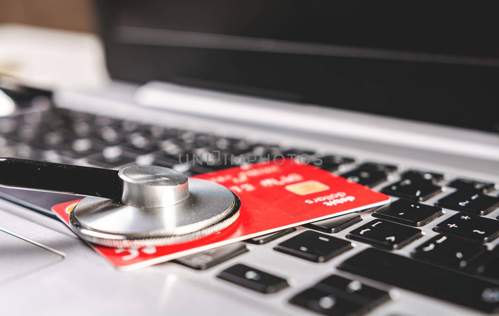 Stethoscope and credit card on the keyboard. Medical healthcare cost concept.