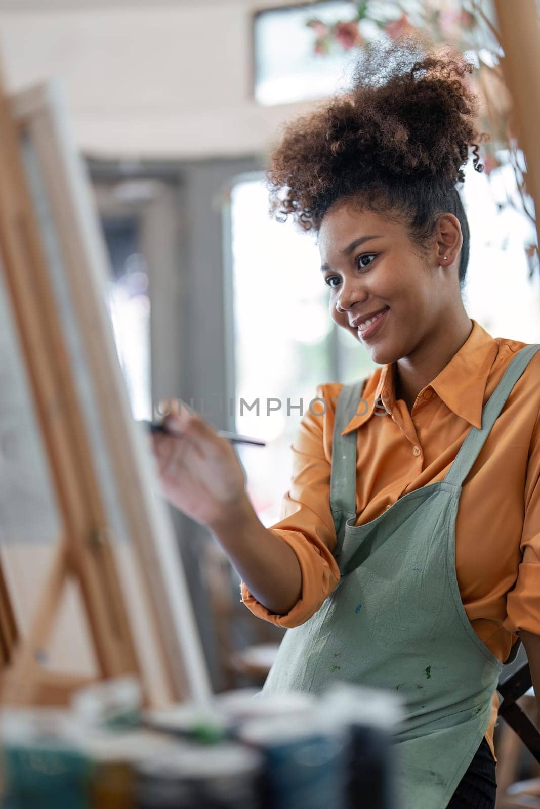 Professional African American female artist painting on canvas in studio. Woman painter painting at an painting studio.