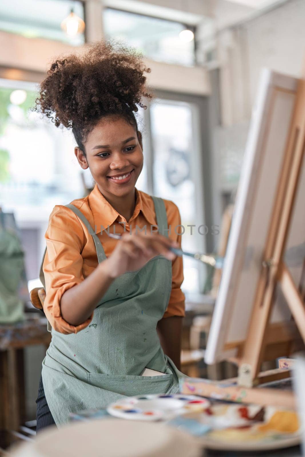 Professional African American female artist painting on canvas in studio. Woman painter painting at an painting studio.