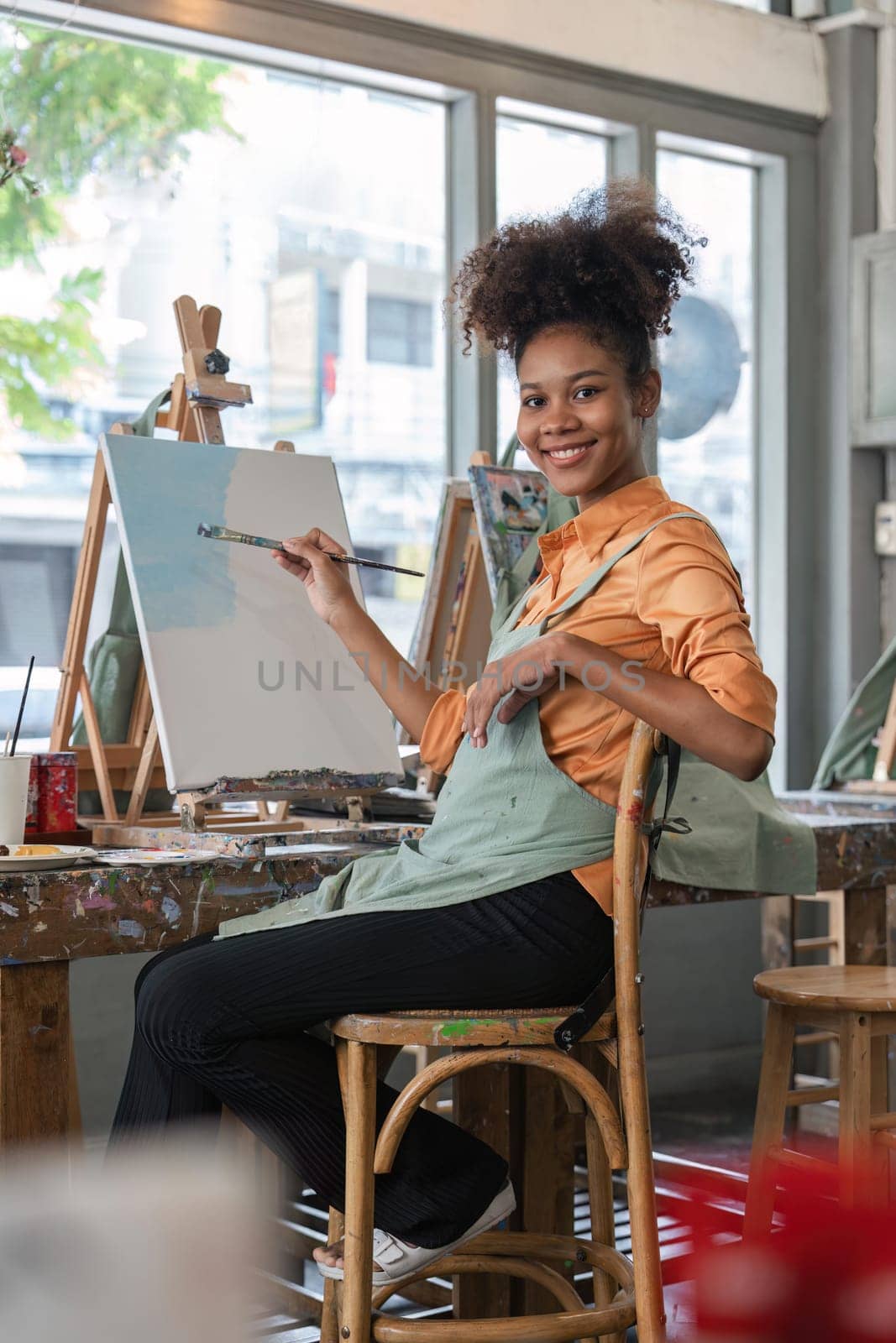 african american female artist painting on canvas doing some art projects on her studio workshop.