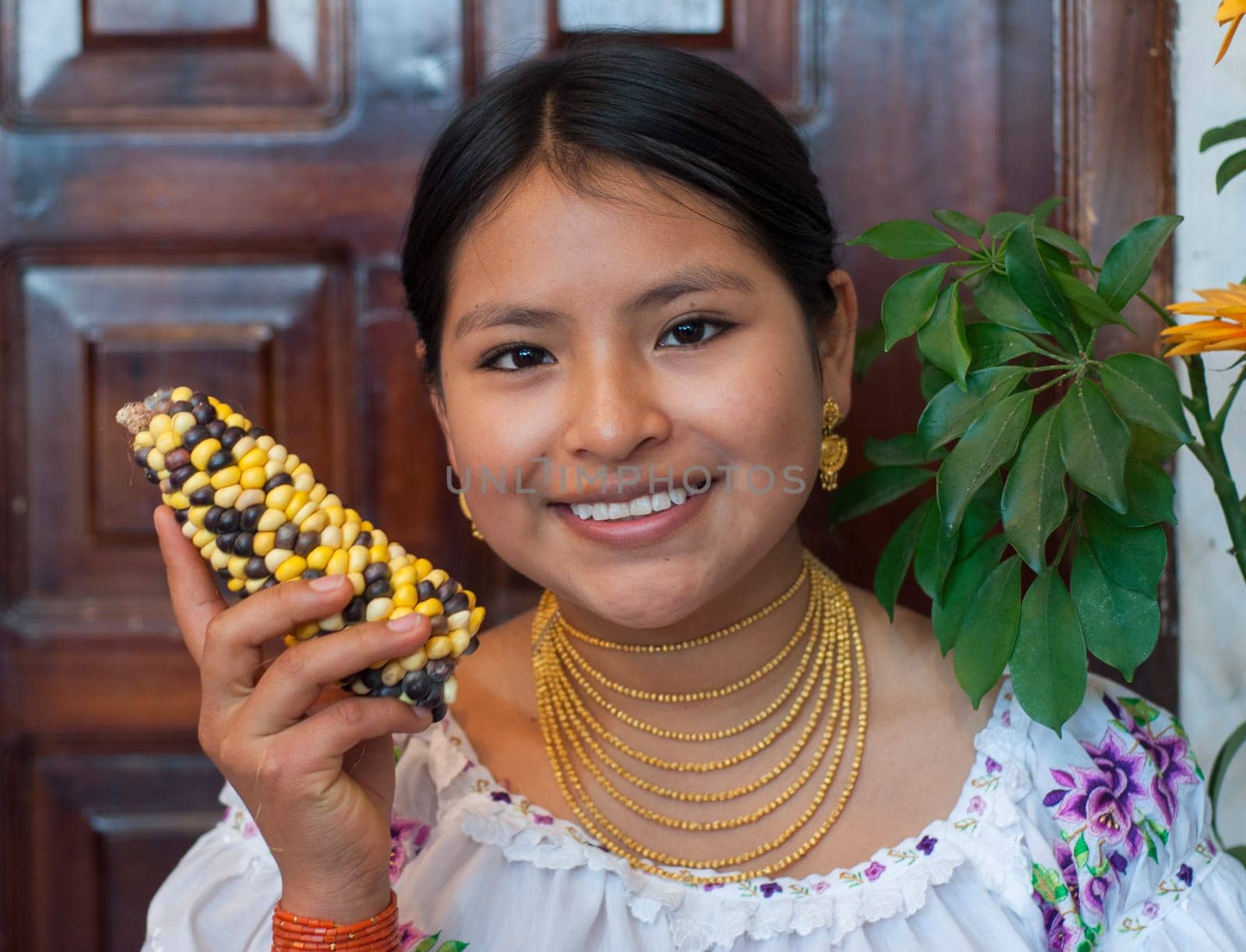 closeup of a beautiful young indigenous woman smiling at the camera with a sweet look while holding an ear of corn in her hand. High quality photo