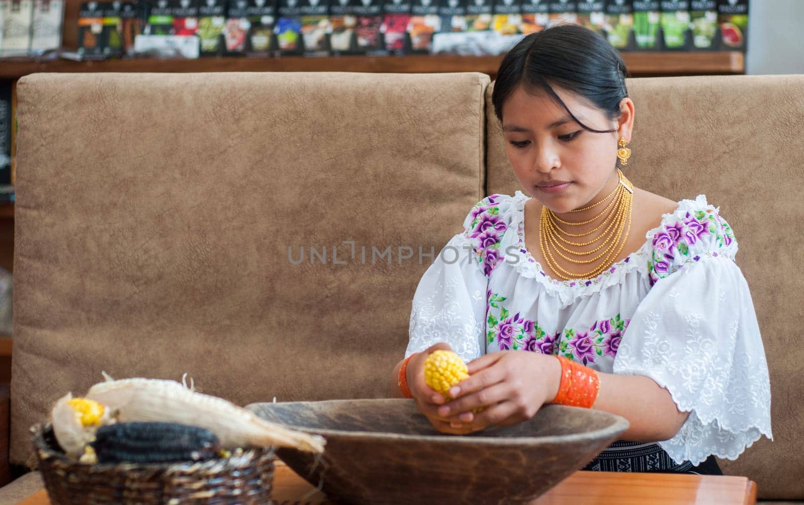 copyspace of a young indigenous woman from ecuador shelling an ear of yellow corn. High quality photo