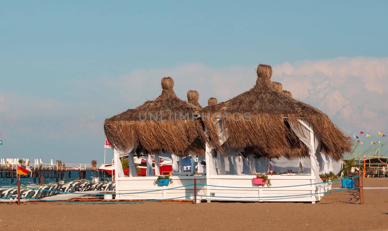 Two luxurious romantic gazebo with palm leaf roof for relaxing on a tropical sandy beach by claire_lucia