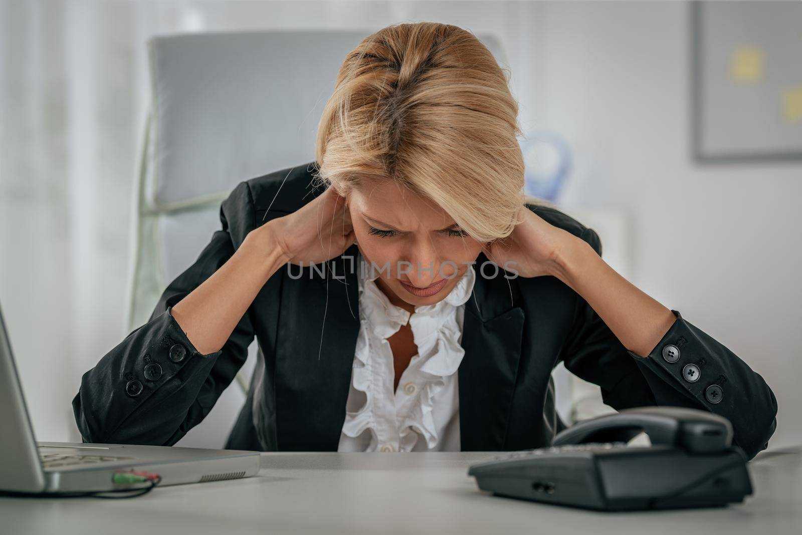 Young tired businesswoman with headache holding her hands on the neck with a pained expression on her face.