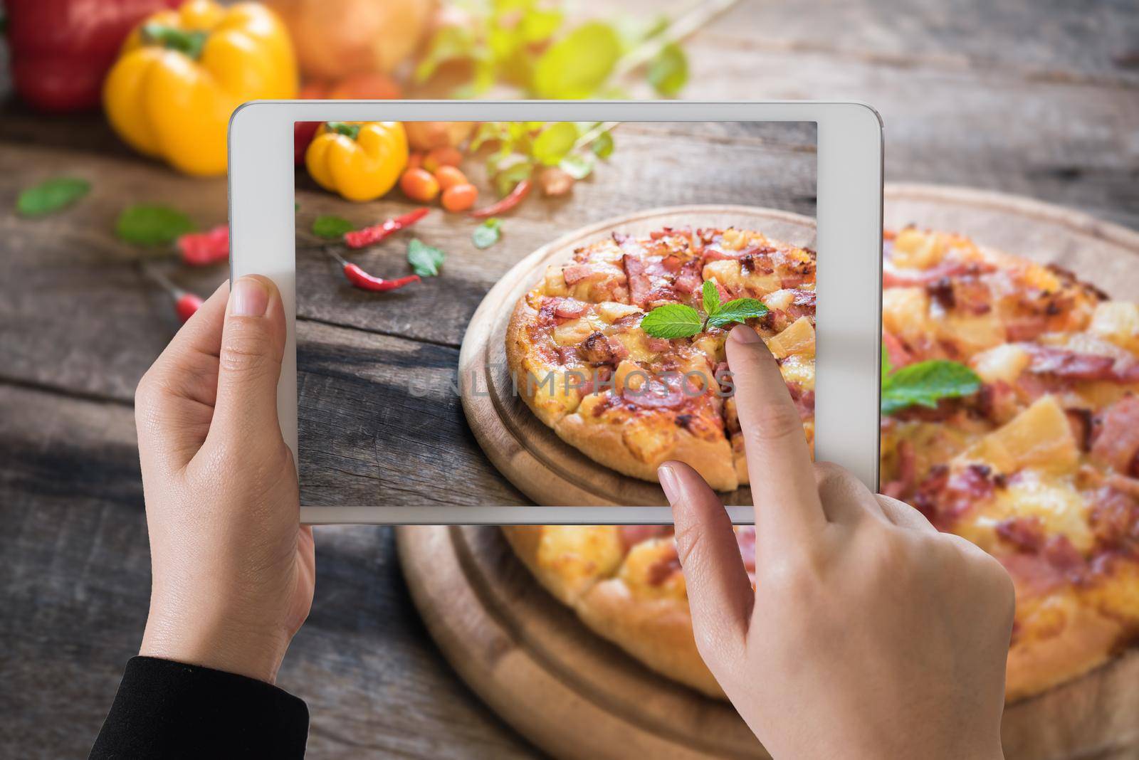 Ipad on delicious italian pizza on wooden table