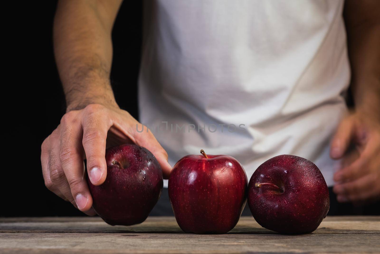 the man holding apples on dark background