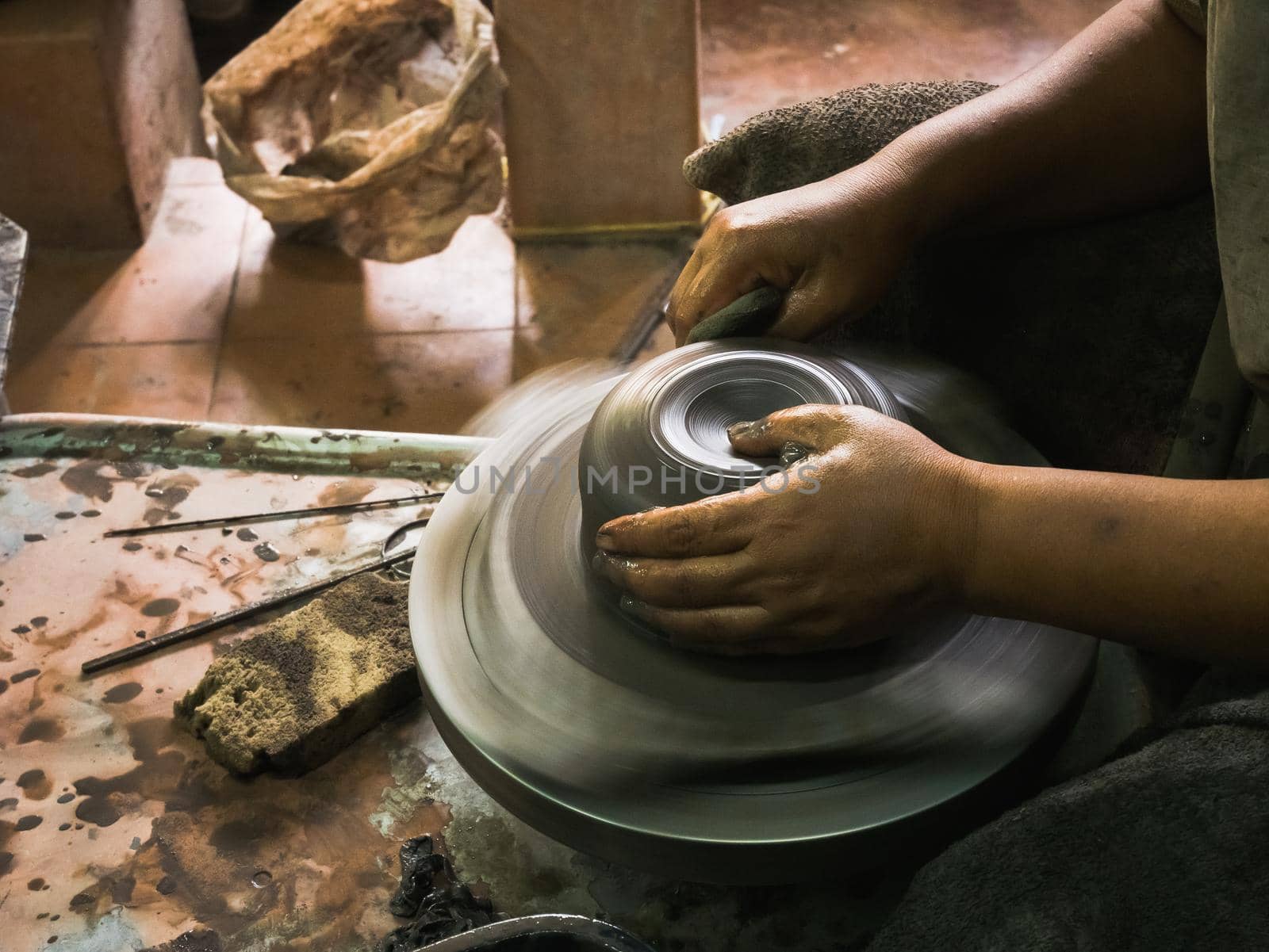 potter's hands shaping soft clay to make an earthen pot by Wmpix