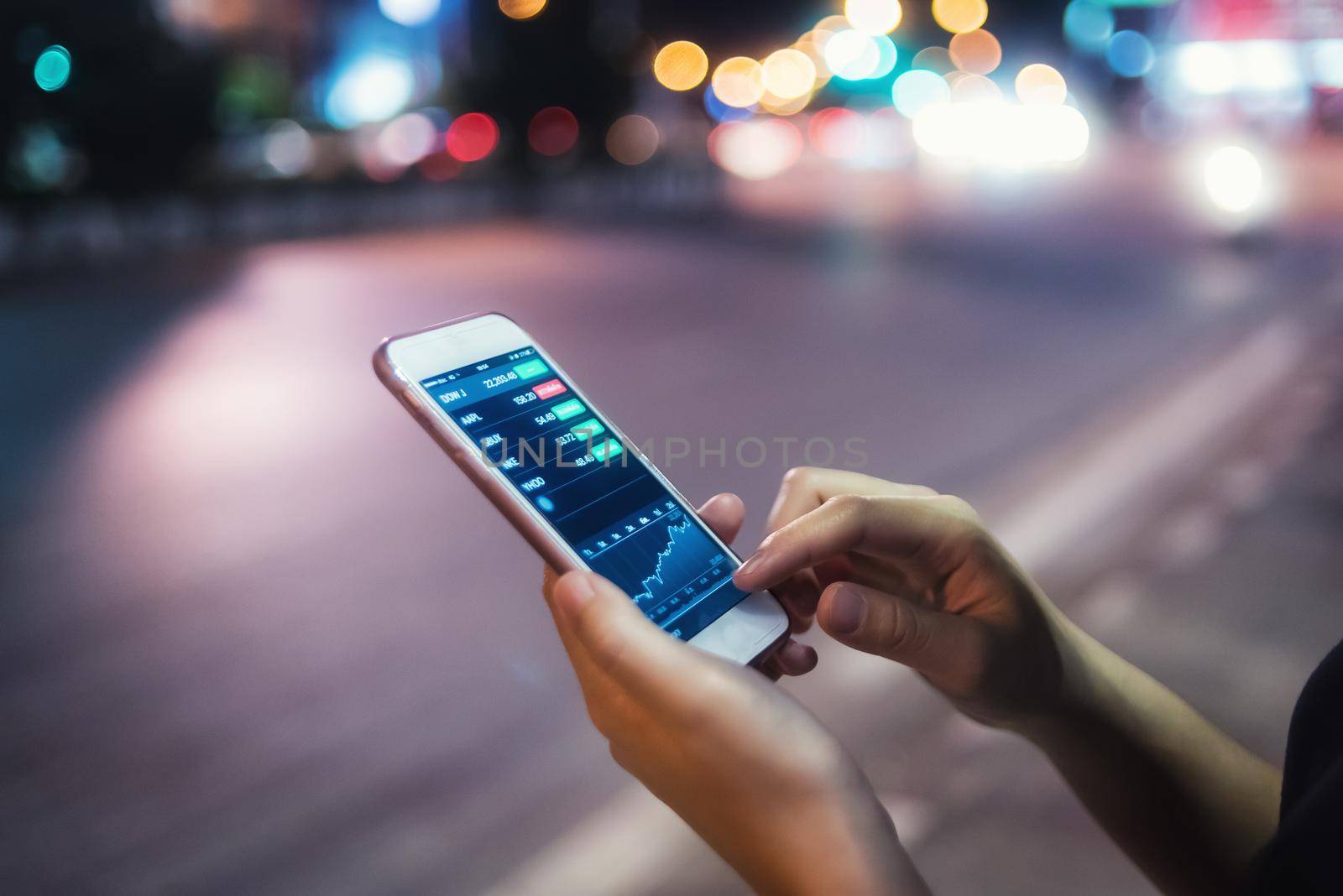 Woman using her mobile phone in the street, night light background by Wmpix