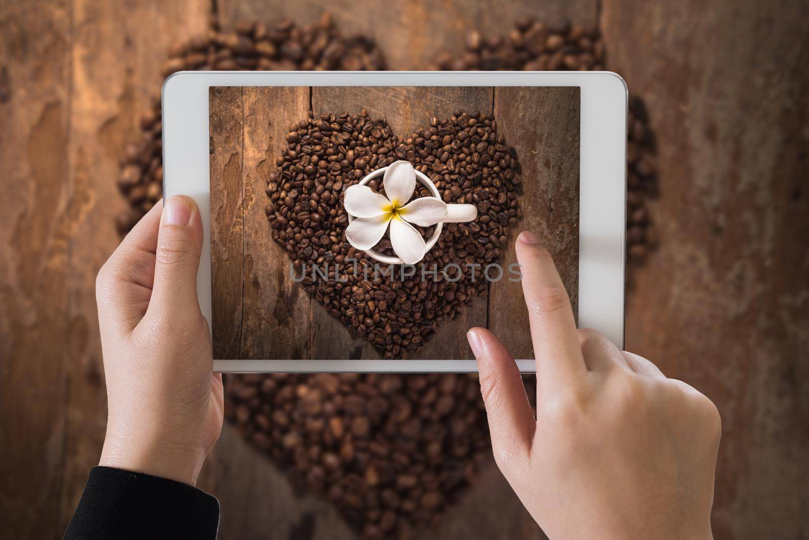 hand girl hoding ipad take photo of cup of coffee on wood table