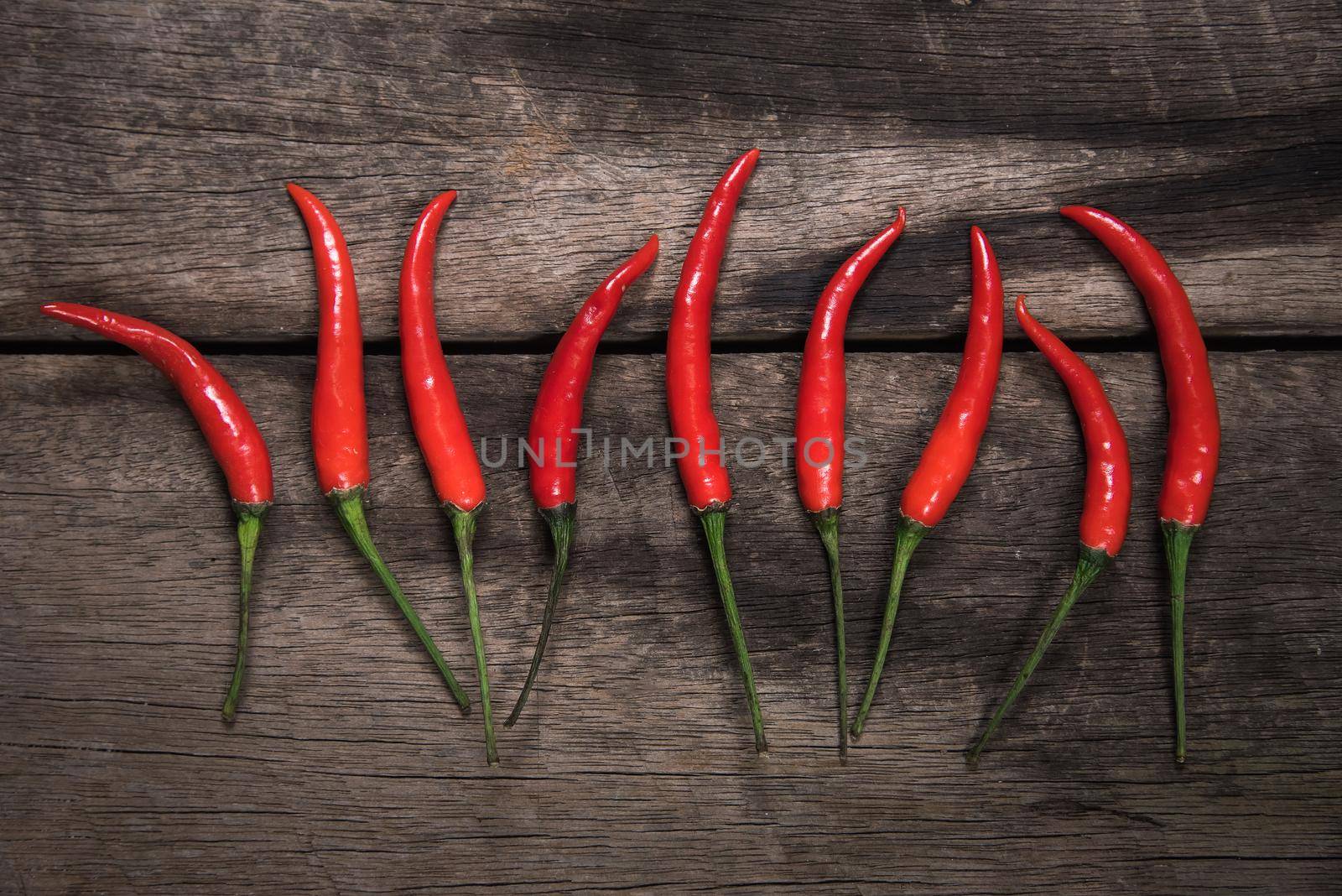 Red chilli on dark wooden table background. food concept by Wmpix