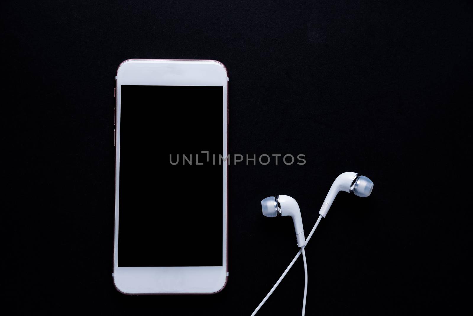 Mobile phone with earphone on dark background by Wmpix