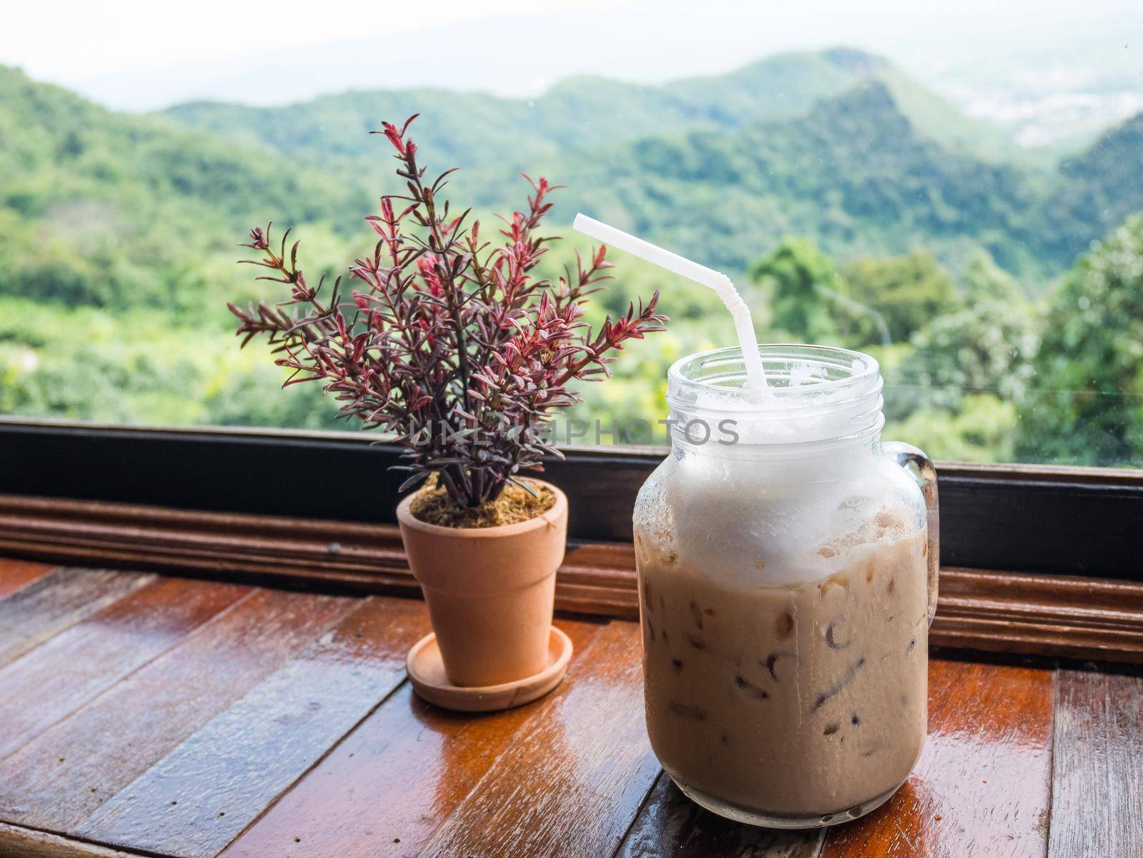 Iced coffee on table with mountain view background by Wmpix