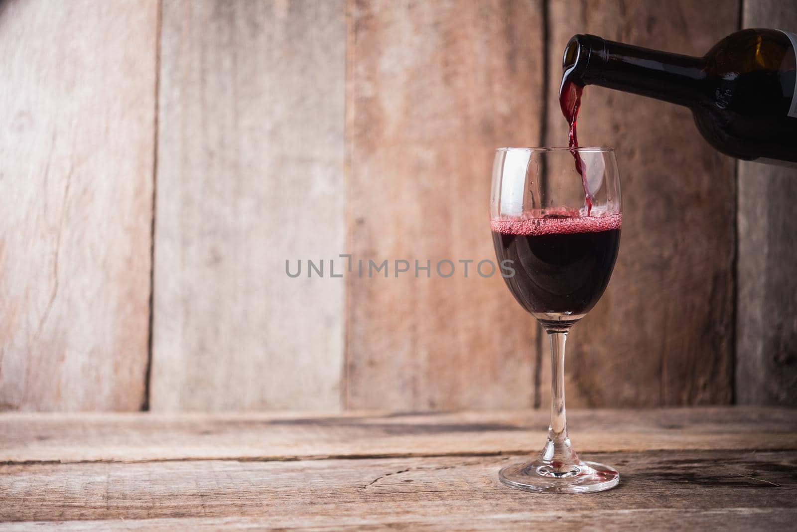 pouring wine into glass on wood background