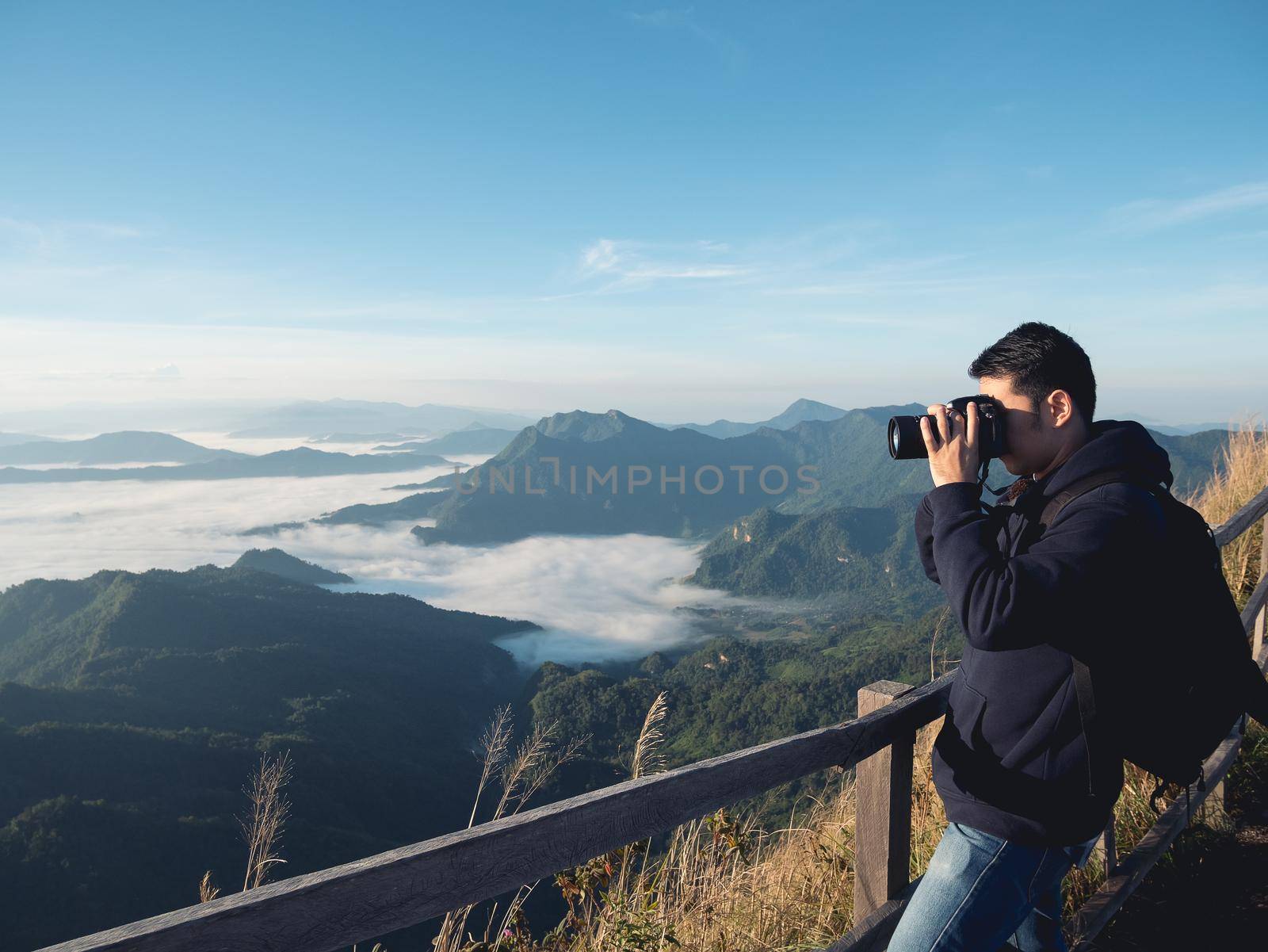 Nature photographer man taking photos in the mountains by Wmpix