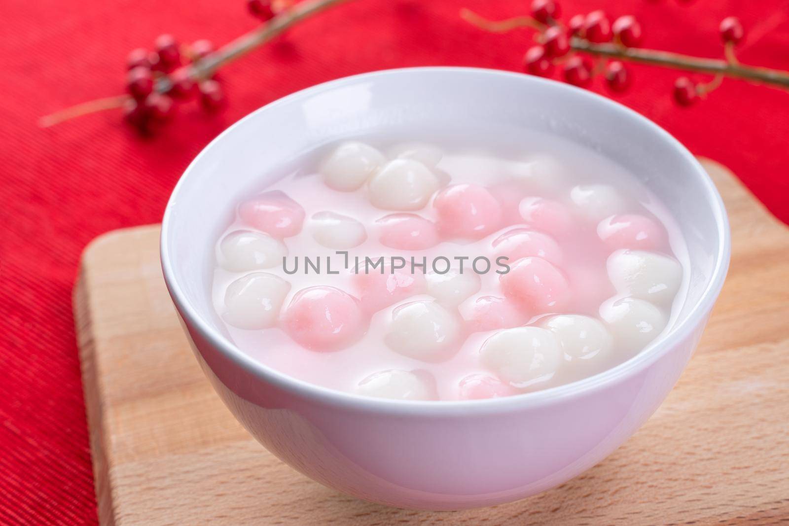 Tang yuan, tangyuan, delicious red and white rice dumpling balls in a small bowl on red background. Asian festive food for Chinese Winter Solstice Festival, close up.