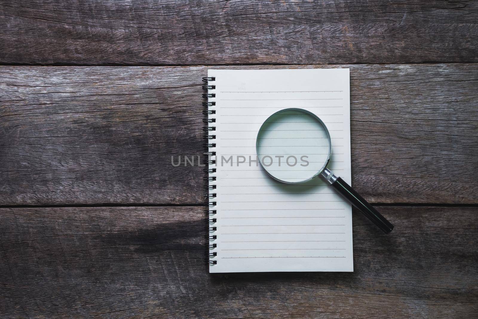 note book and Magnifier on wood table