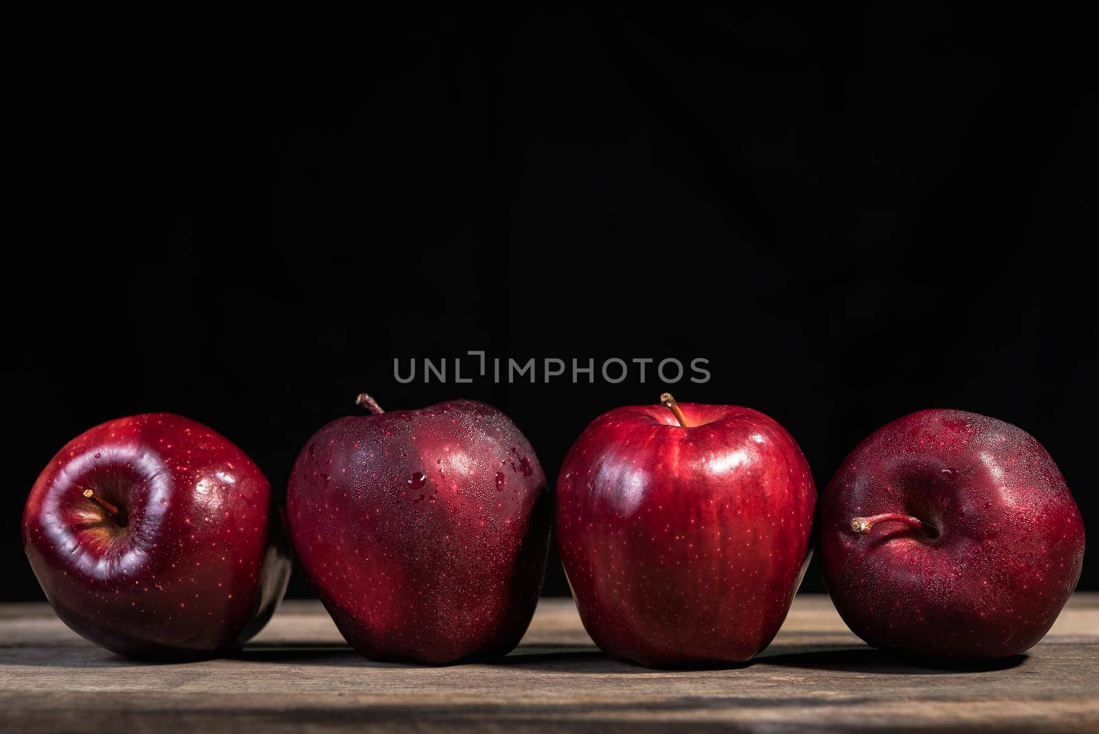 Red apple on wood table, black background