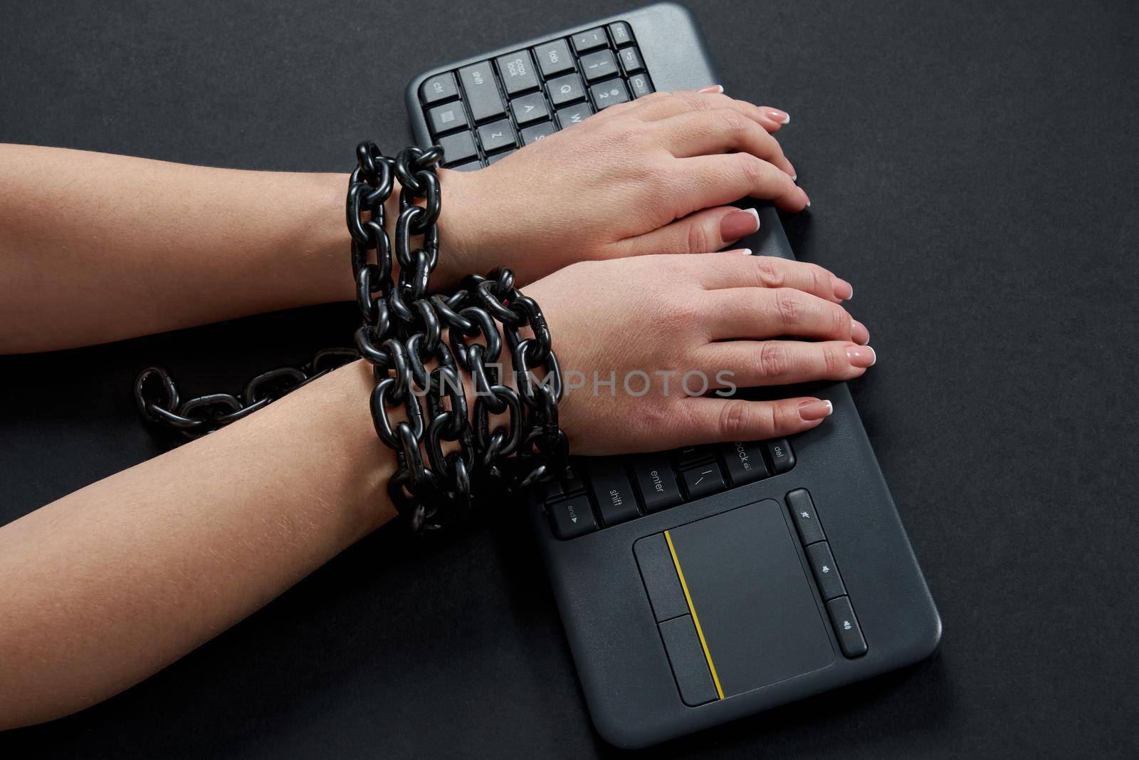 Female hands Chained to black Keyboard, addiction concept