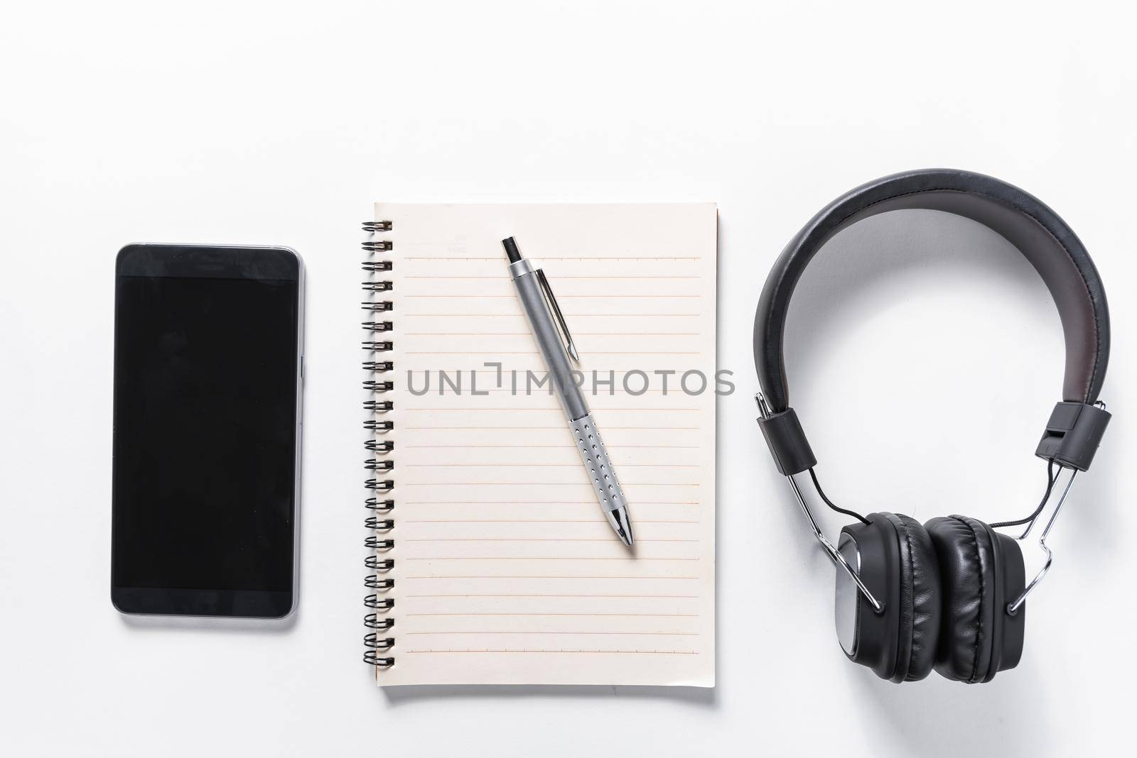 flat lay of earphone, mobile phone and notebook on white background, music concept