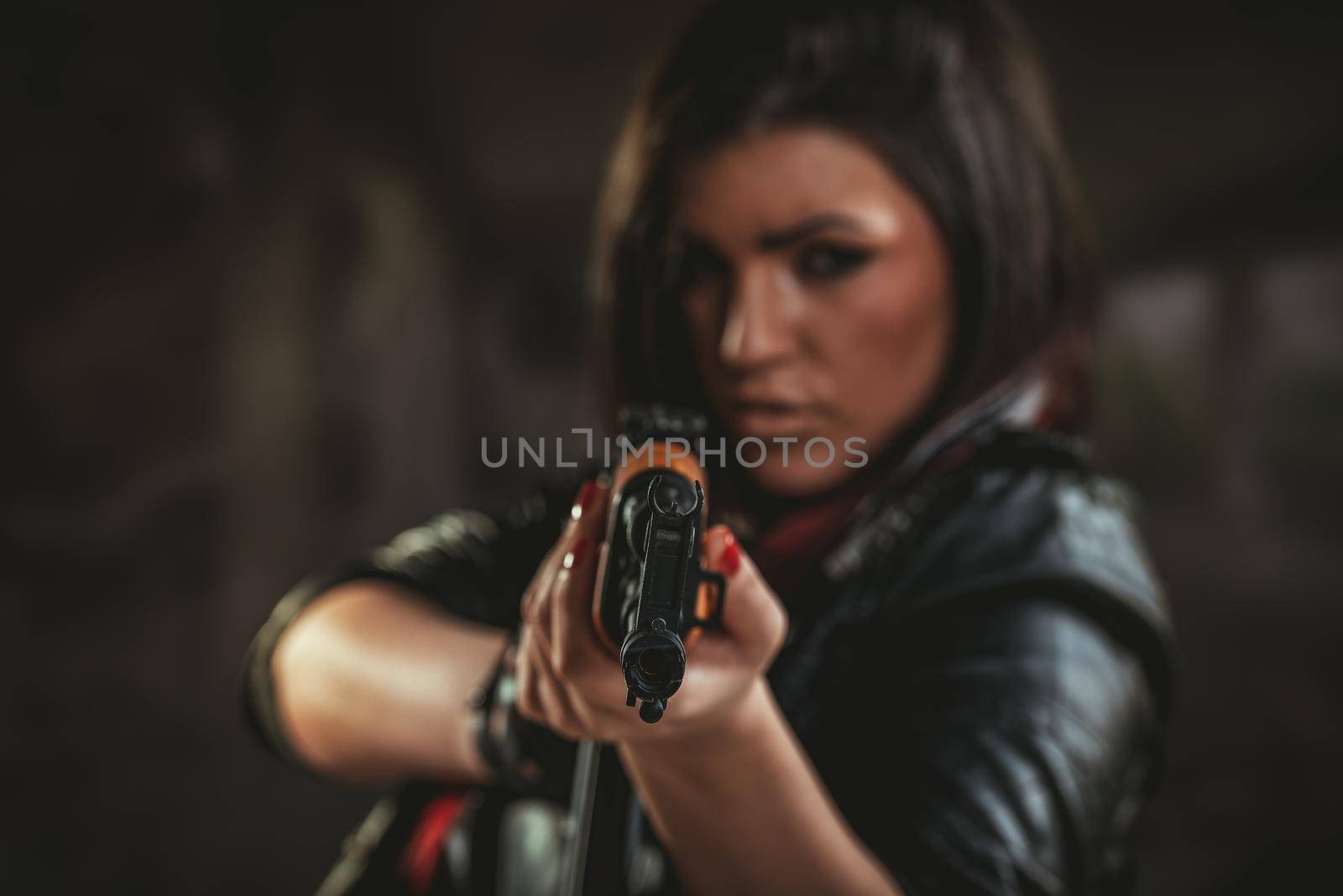 Attractive girl standing in the attitude of aiming and looking through the sight automatic rifle.