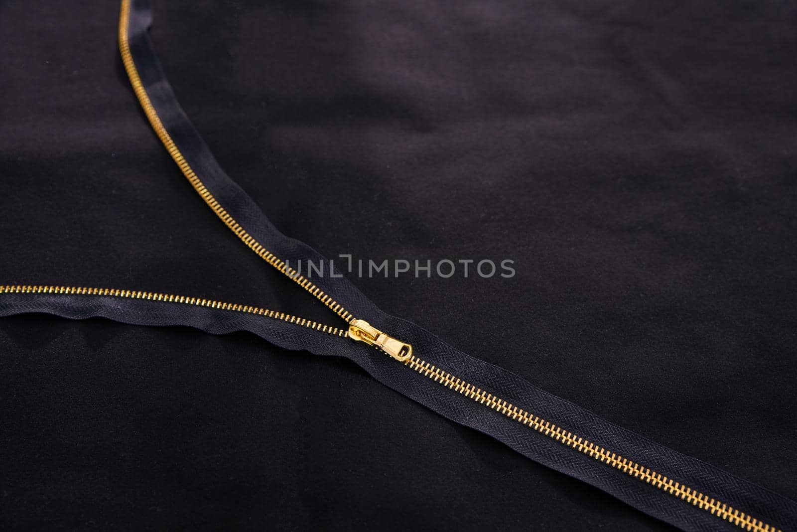 Open golden zipper on black fabric