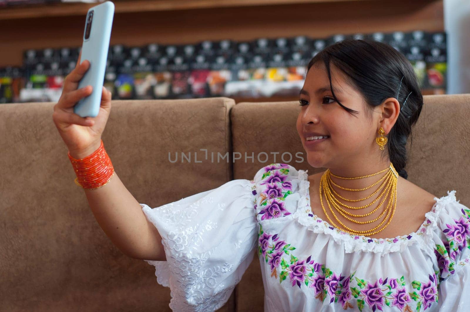 beautiful indigenous woman in traditional dress from otavalo ecuador smiling while taking a selfie with her cell phone. High quality photo