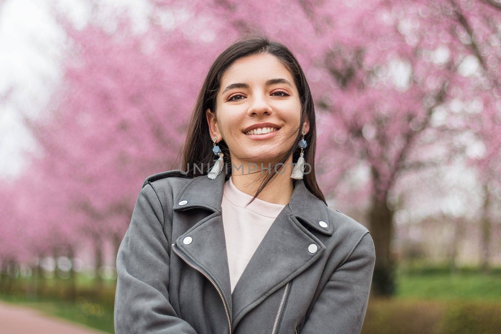 Portrait of independent multi-ethnic Turkish woman 25s with stylish make-up and casual clothes smiling in the street.