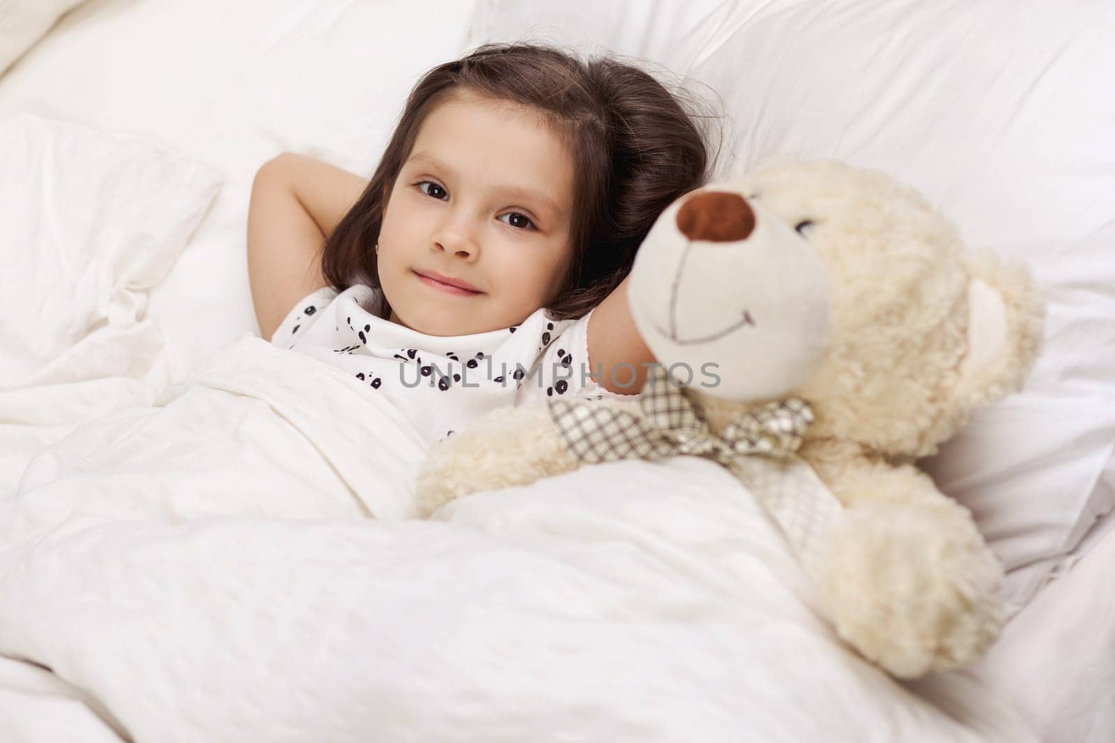 cute little child girl wakes up from sleep in bed in the morning
