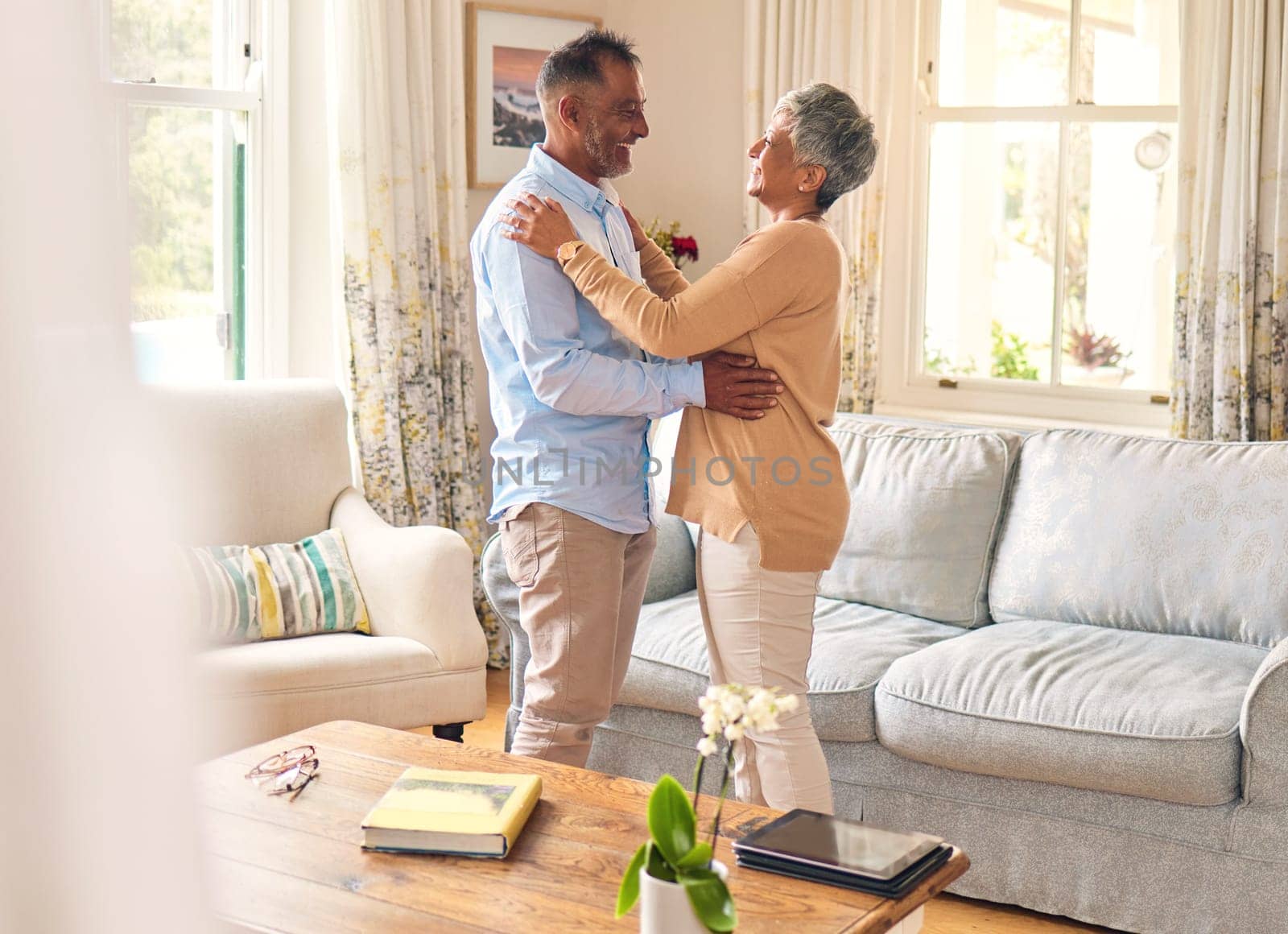 Love, romance and dance with a senior couple in the living room of their home together for bonding. Marriage, retirement or bonding with an elderly man and woman dancing in the lounge of their house by YuriArcurs