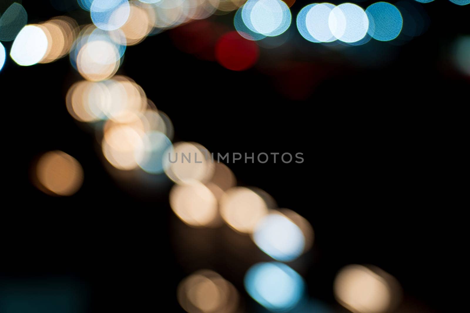 Abstract defocused background of vibrant colored circles forming patterns on a dark night highway, creating a celebration of illuminated lights. Perfect backdrop with blurred motion and close-up photographic effects. Space for text in the darkness.