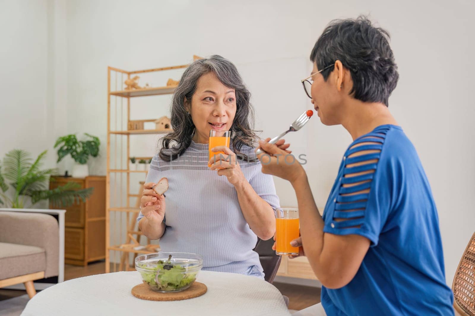 Two elderly girl friend enjoy eating healthy food at house.