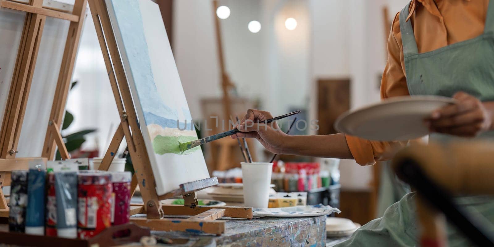 Close up of african american male painter at work painting on canvas in art studio. creation and inspiration at an artists painting studio.