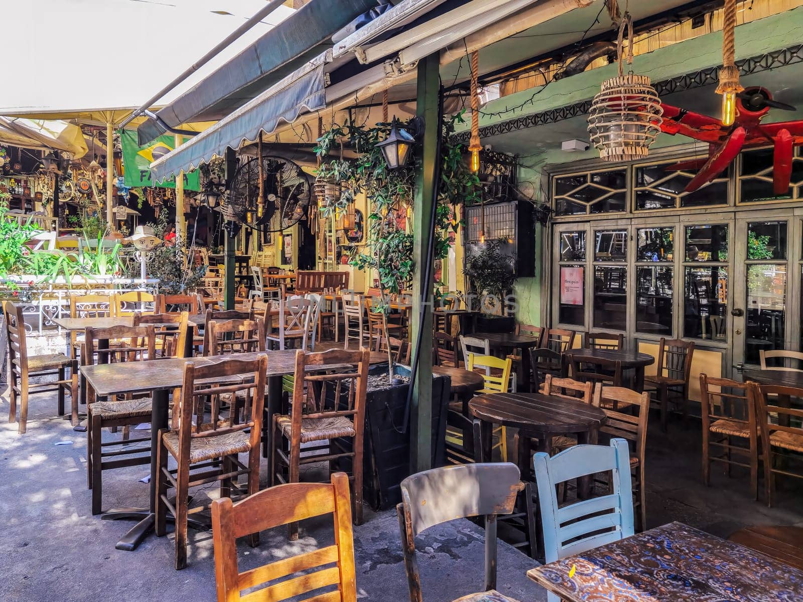 Thessaloniki, Greece - June 30 2023: Day view of the empty traditional outdoor seating area of taverns with colorful chairs, tables and vintage decoration at the historic Bit Bazaar area.