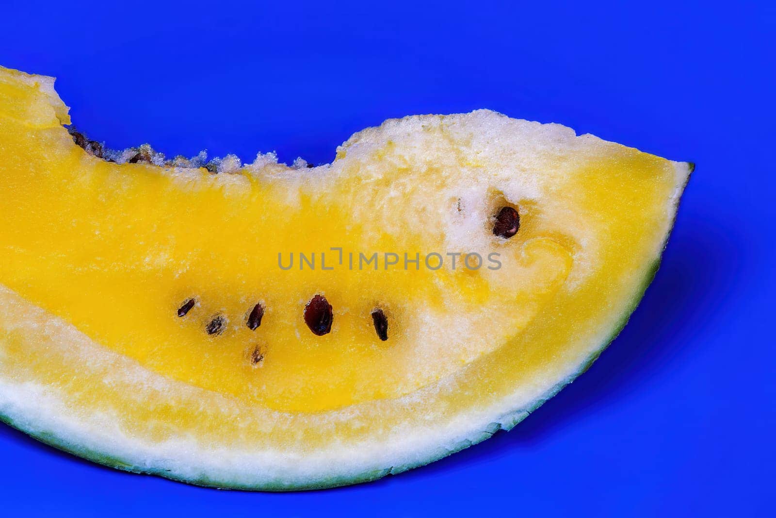 A slice of sweet fresh yellow watermelon served on a blue dish, against colorful background.