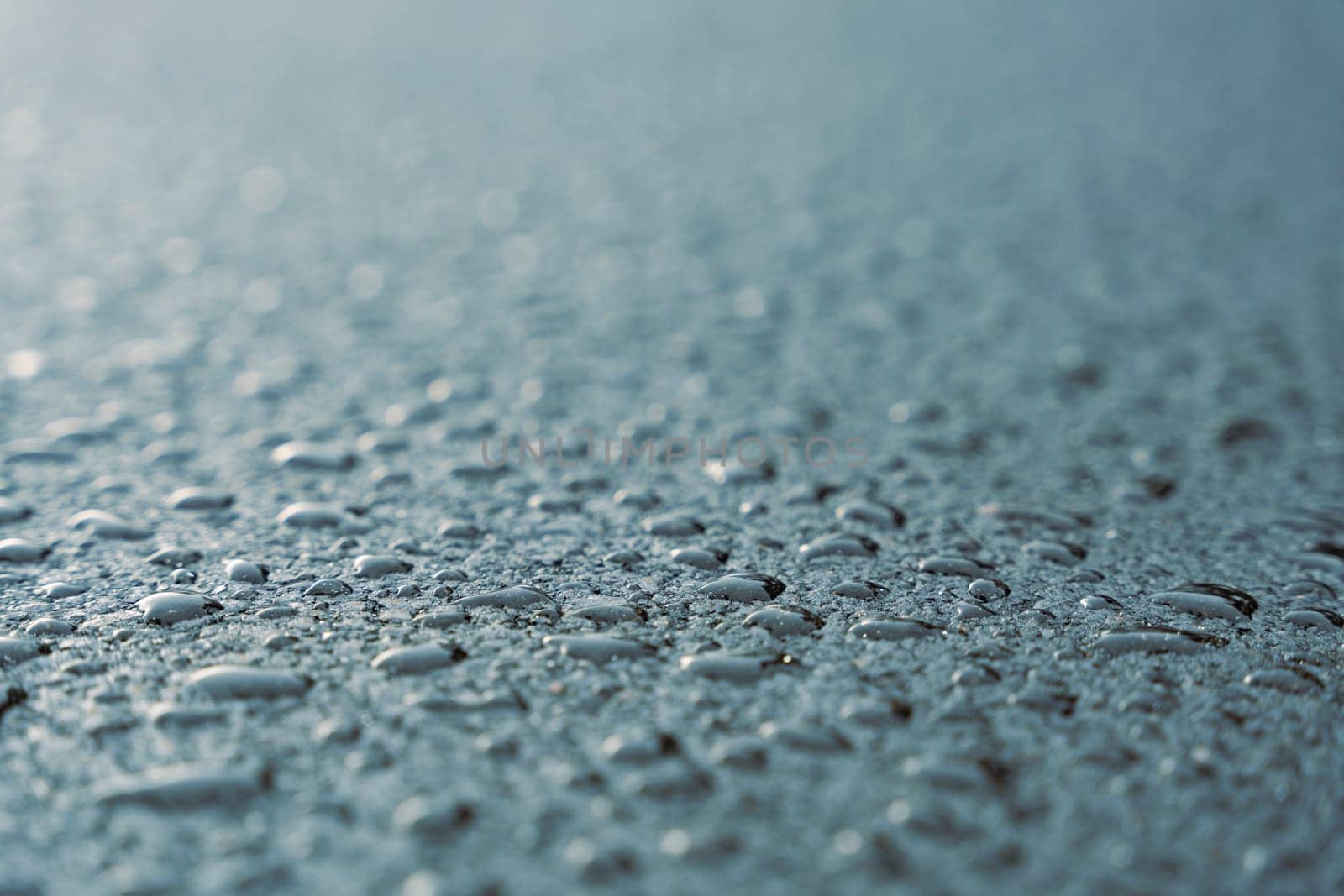 Raindrops on fresh asphalt. water drops on black. Abstract black background with drops. Highway covered with water drops, copy space. Water on the sidewalk