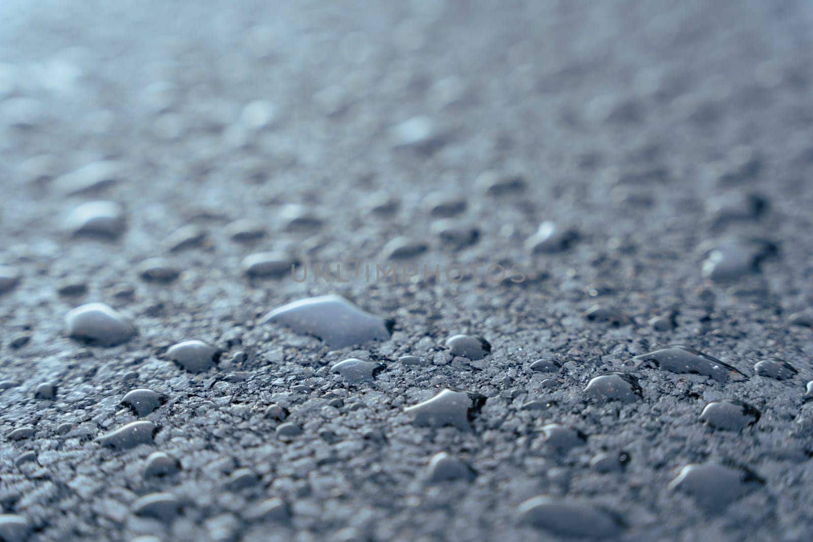 Large Raindrops on fresh asphalt. water drops on black. Abstract black background with drops. Highway covered with water drops, copy space. Water on the sidewalk