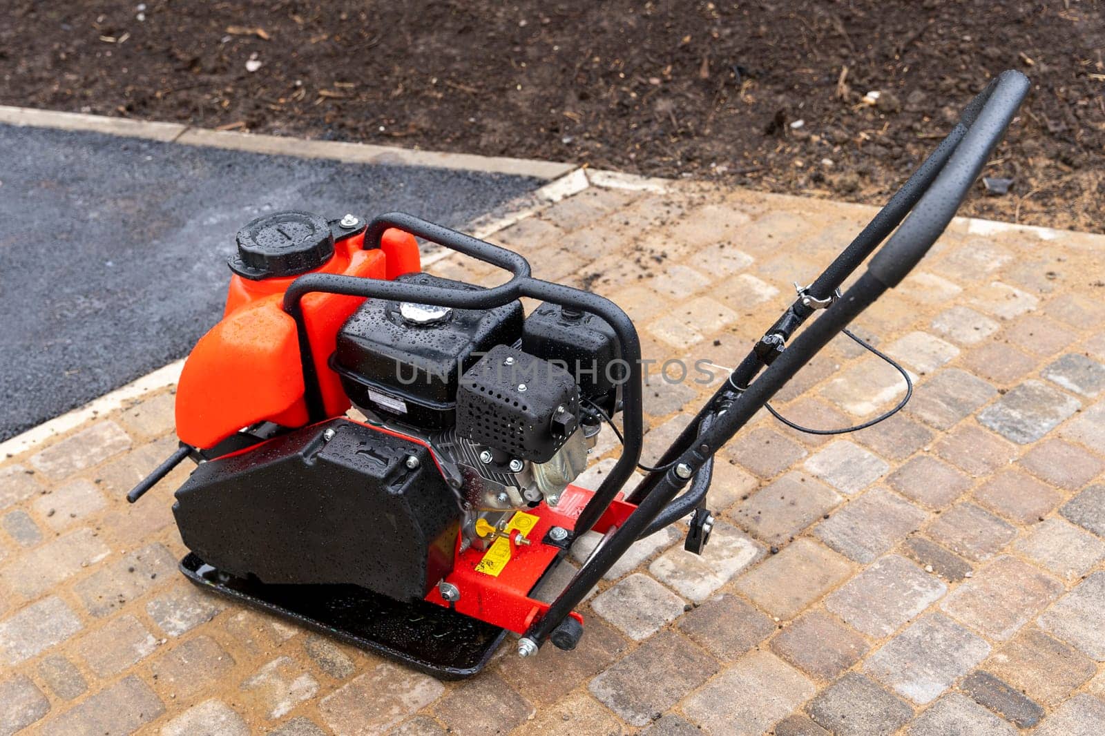 Gasoline Vibrating rammer with a vibrating plate on a construction site. Compaction of the soil before laying paving slabs. tools on the construction site.