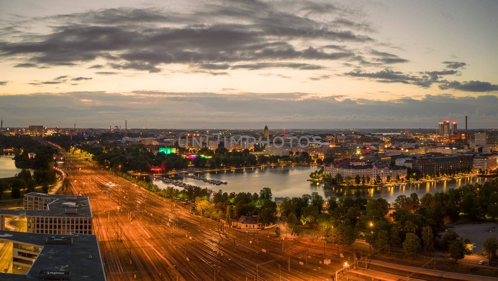 Empty train tracks glow amid city lights with dawn light in sky. High quality photo