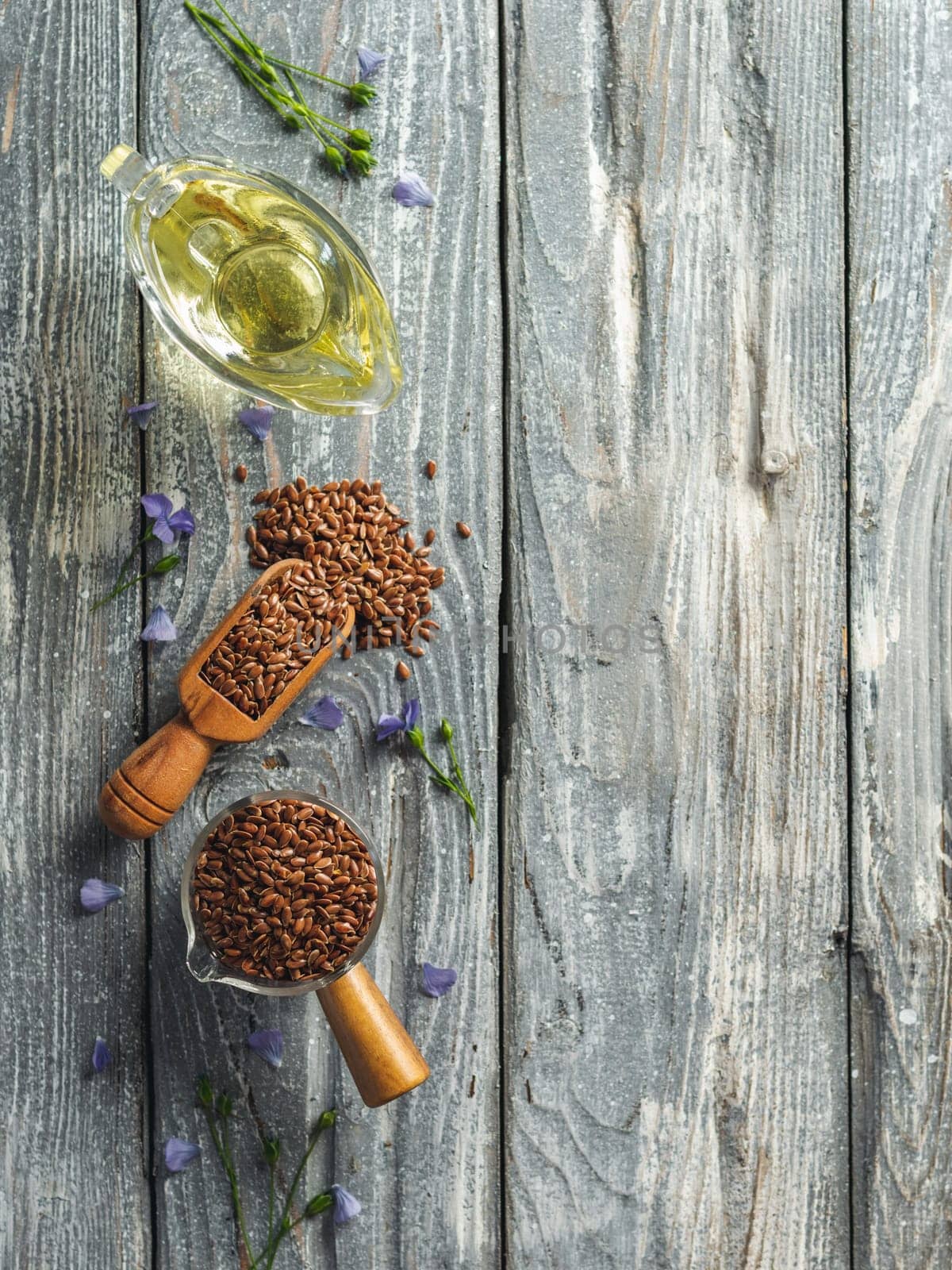 Flax seeds and flax oil. Brown linen seeds and flaxseed oil on old gray wooden background. Copy space. Top view or flat lay. Vertical.