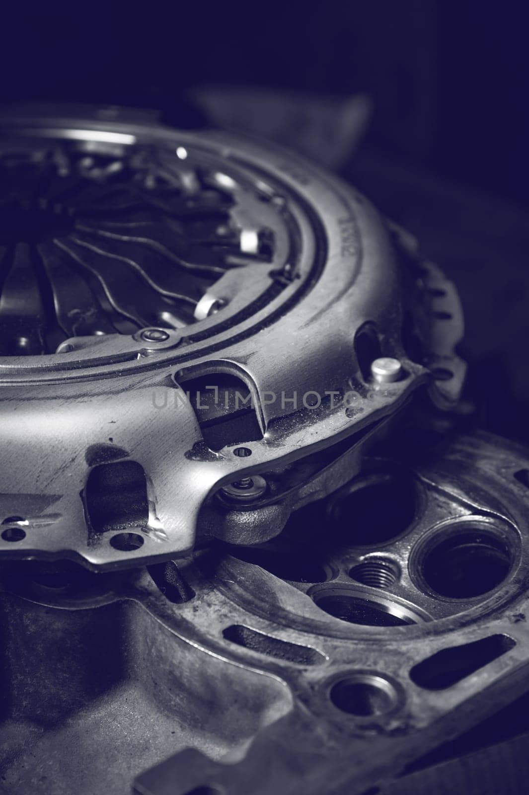 A new clutch basket lies in the workshop on the cylinder head of the internal combustion engine. Toned image.